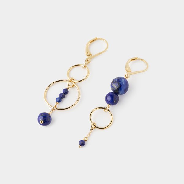 Une paire de boucles d'oreilles asymétriques bleues et or, posés à plat sur fond blanc