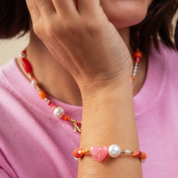 Femme portant un bracelet perles multicolores avec cœur rose en résine et perles d'eau douce, bijoux artisanaux collection Riviera Mademoiselle Nuage