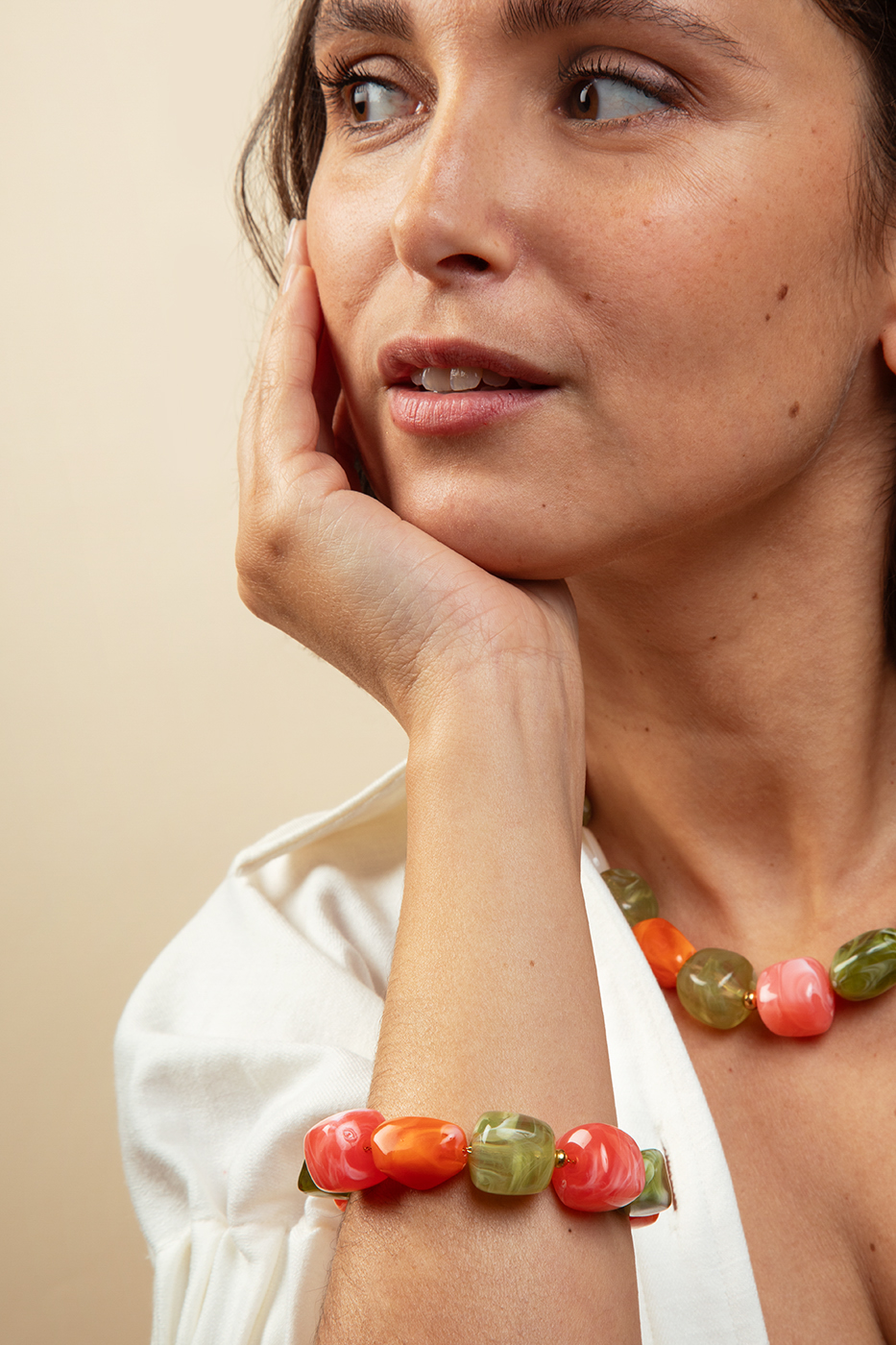 Femme portant un bracelet de perles colorées en galets acryliques nacrés corail et vert olive, bijoux artisanaux collection Riviera Mademoiselle Nuage